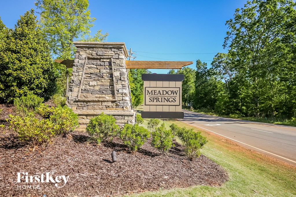 A sign for Meadow Springs is in front of a stone pillar.