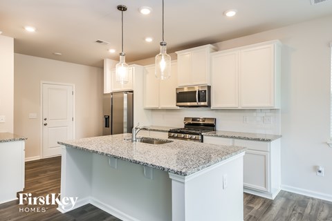 A kitchen with a granite countertop and a stainless steel refrigerator.