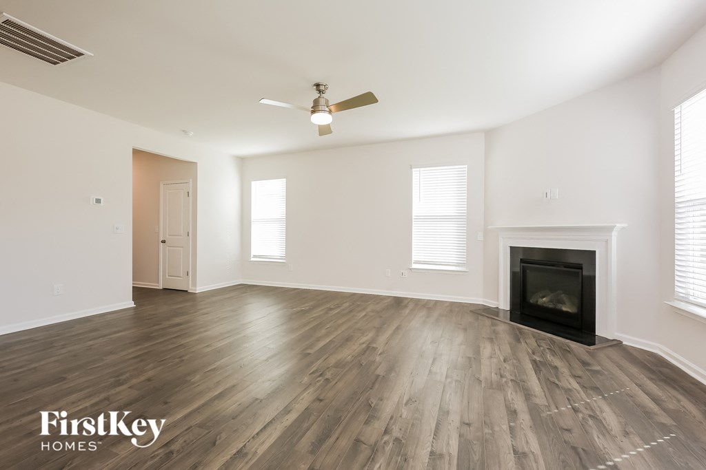 A spacious room with a fireplace and wood flooring.