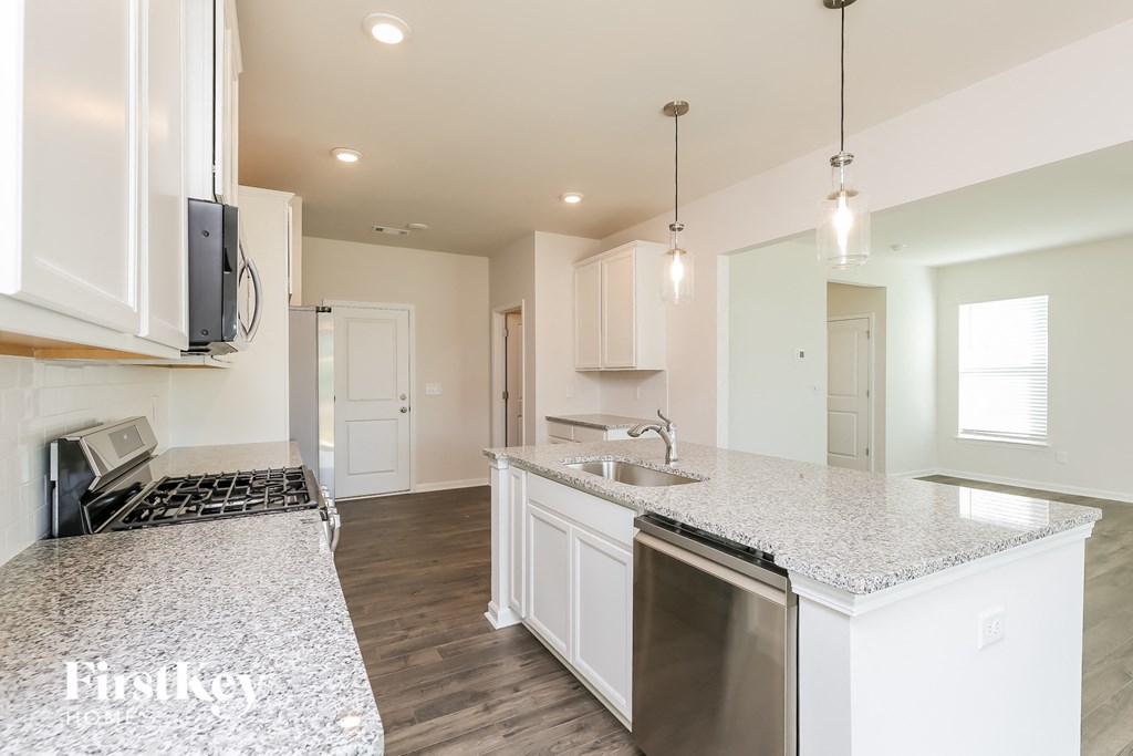 A kitchen with white cabinets and a granite countertop.
