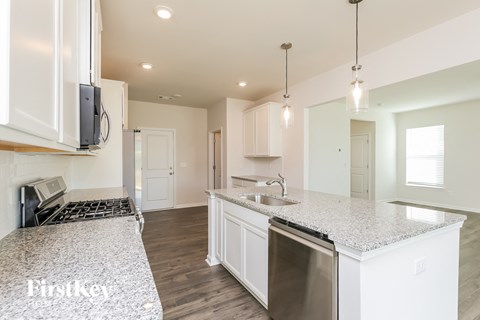A kitchen with white cabinets and a granite countertop.
