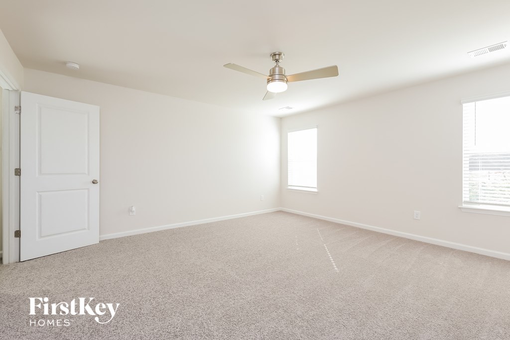 A spacious room with a ceiling fan and a door.