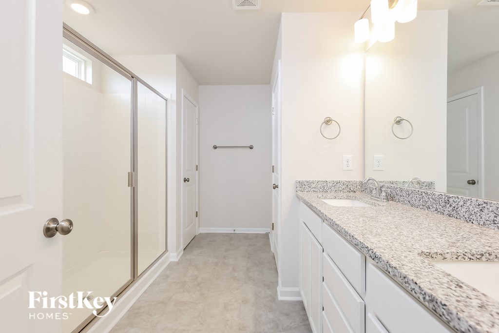 A bathroom with a marble countertop and a walk-in shower.
