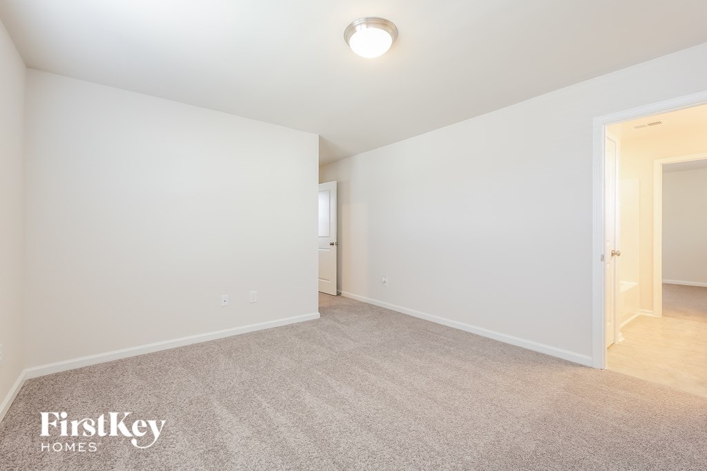 A spacious room with a carpeted floor and a single light fixture on the ceiling.