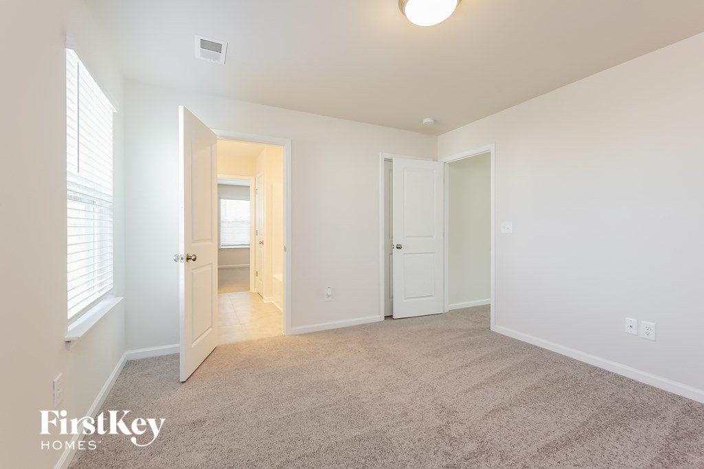 A carpeted room with a doorway leading to another room.