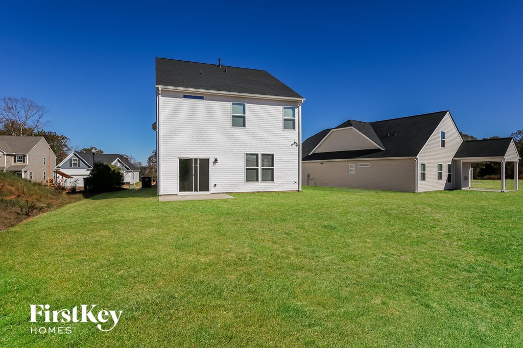 A white house with a black roof is in the foreground with a blue sky in the background.