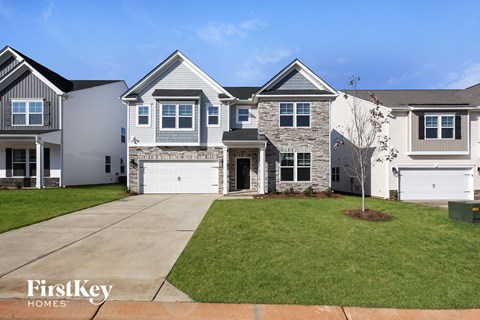 a white and gray house with a driveway and a lawn