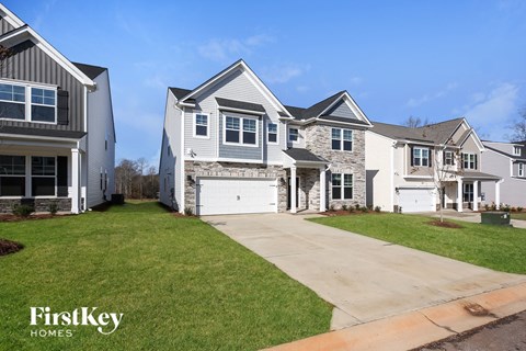 a white and gray house with a driveway and a lawn