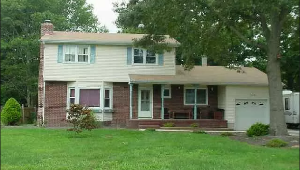 a white and brick house with a yard and trees