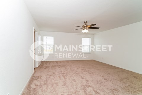 a living room with a carpet and a ceiling fan