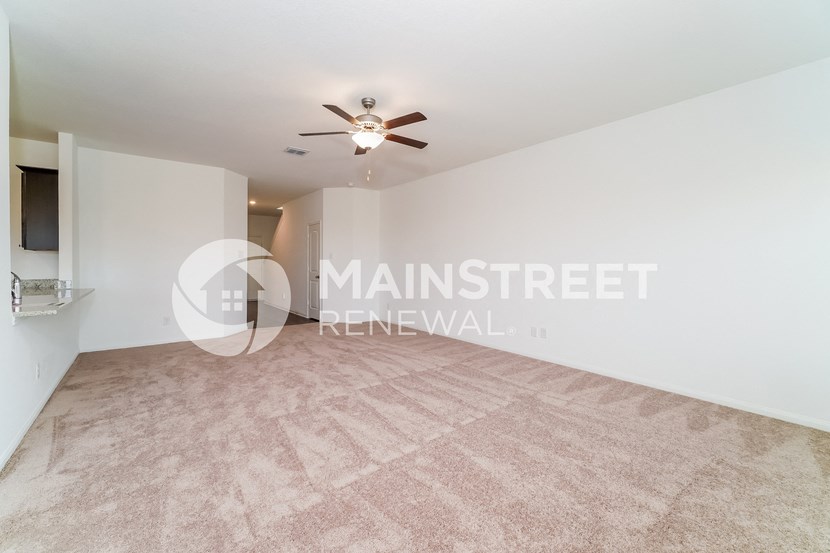 a living room with a carpet and a ceiling fan