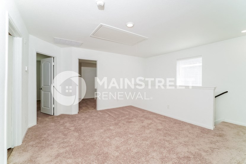 a renovated living room with carpet and a door to a hallway