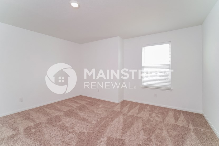 renovated living room with beige carpet and white walls and a window