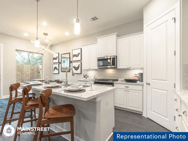 an image of a kitchen with white cabinets and a marble counter top