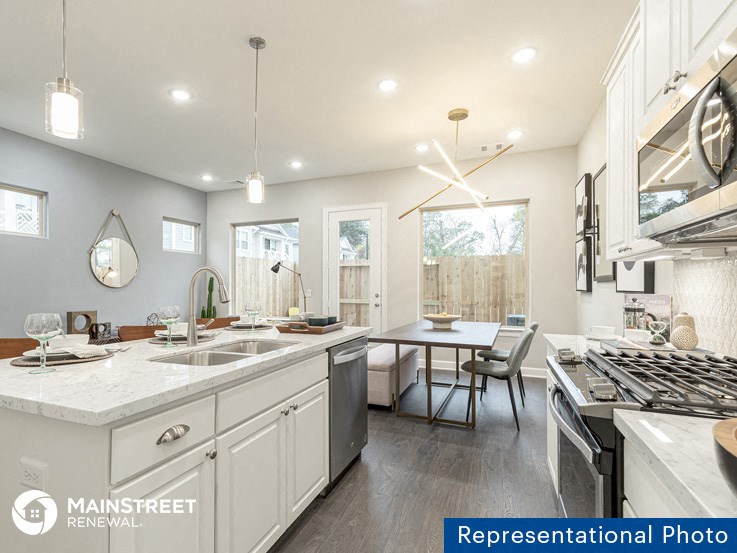 a kitchen and dining room with white cabinets and stainless steel appliances