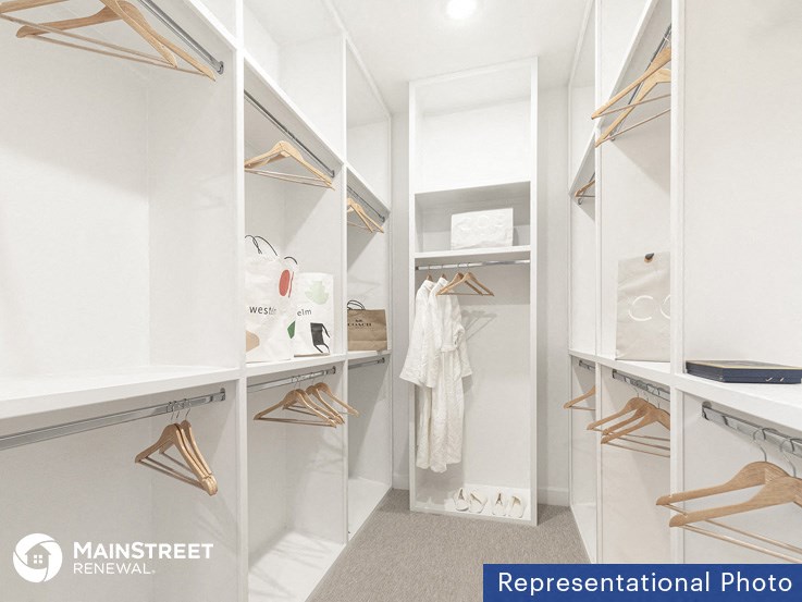 a walk in closet with white cabinets and a white wardrobe