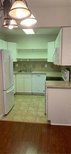 A kitchen with white appliances and wooden floors.