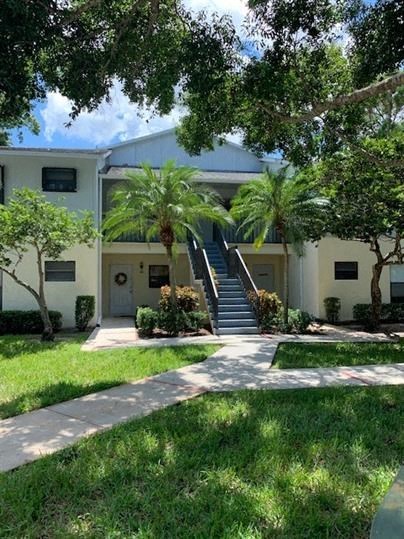 the front of a building with stairs and grass and palm trees