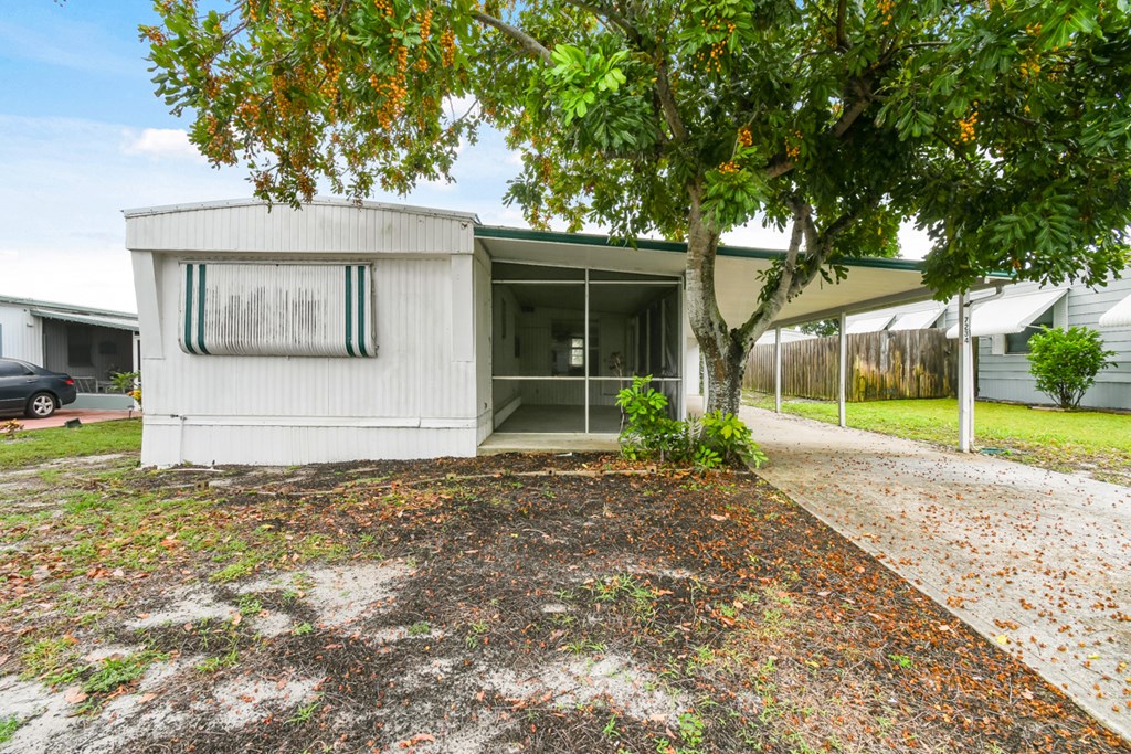A white house with a green tree in front.