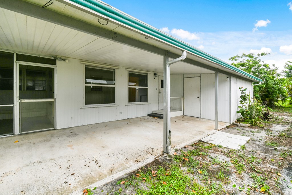 A white building with a green roof and a white door.