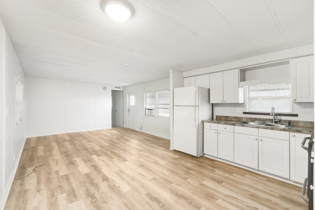 A kitchen with white cabinets and a wooden floor.