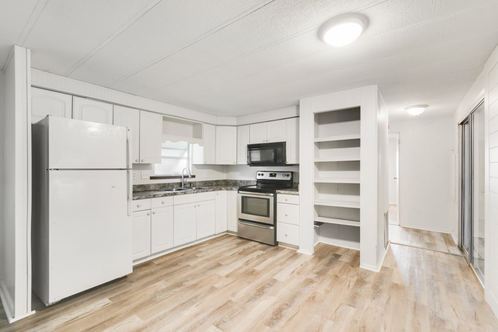 A kitchen with white appliances and wooden floors.
