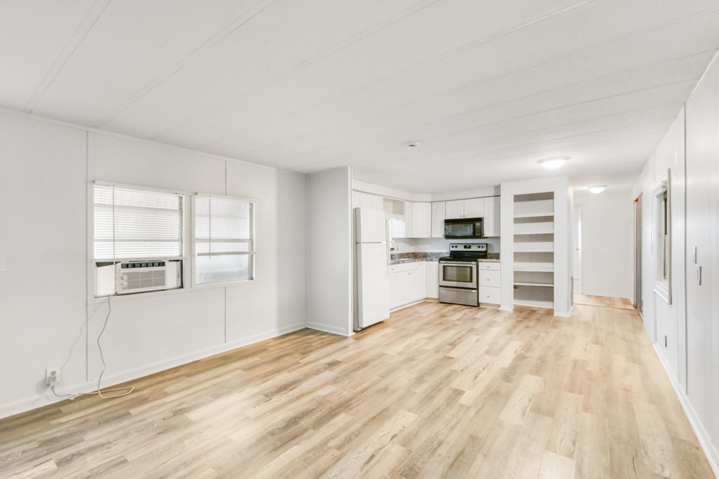 A spacious kitchen with white cabinets and a wooden floor.