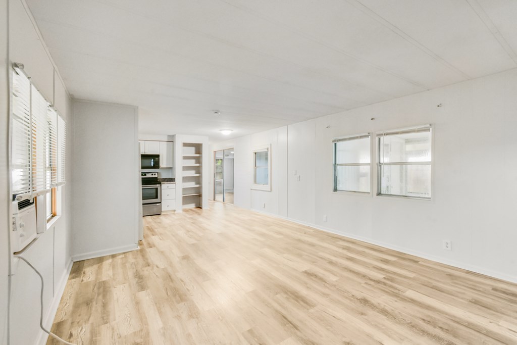 A spacious room with wooden flooring and white walls.