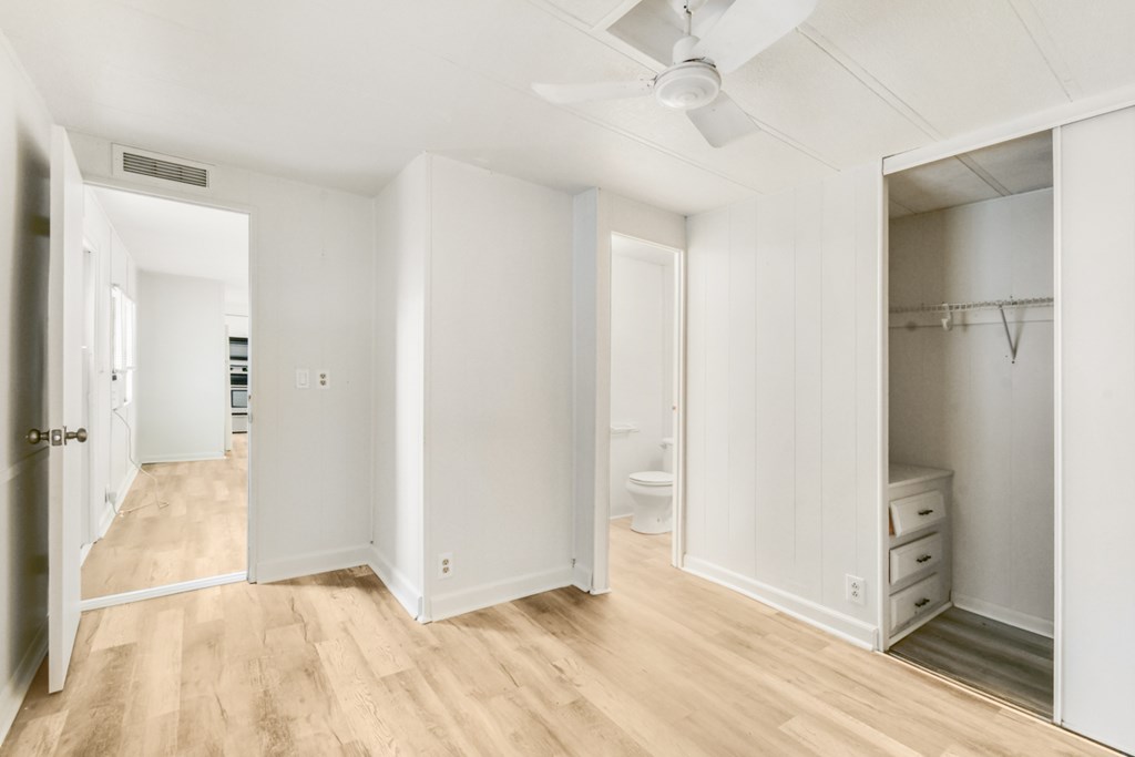 A white room with a ceiling fan and wooden floors.