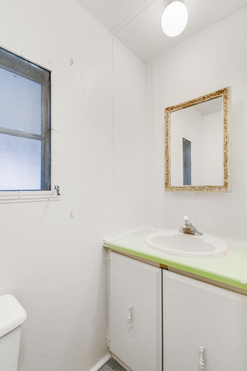 A bathroom with a white toilet, a green sink, and a mirror.