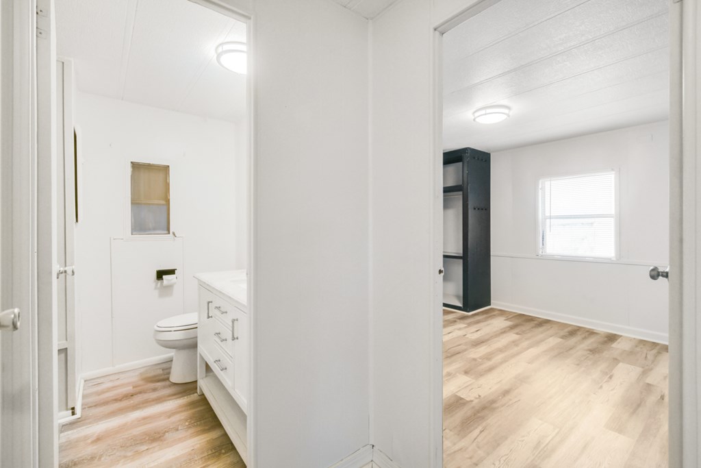 A white bathroom with a toilet, sink, and mirror.