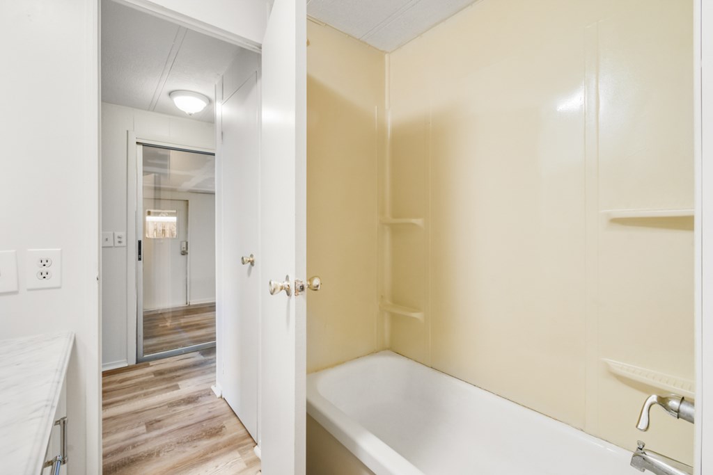 A white bathtub is in a bathroom with a white tub in the hallway.