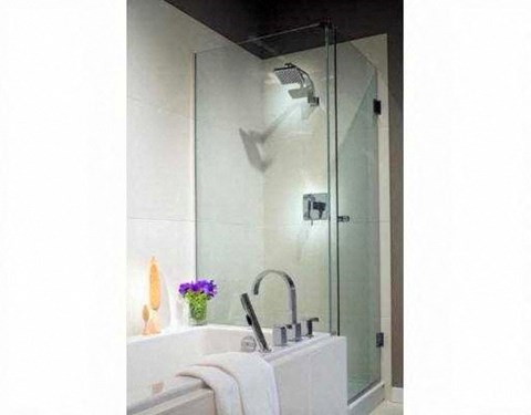 A white sink with a silver faucet and a glass shower door.