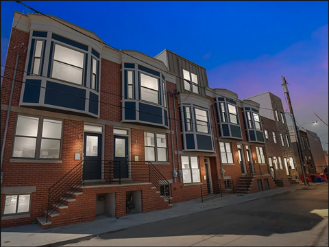 a row of brick apartment buildings on a city street at night