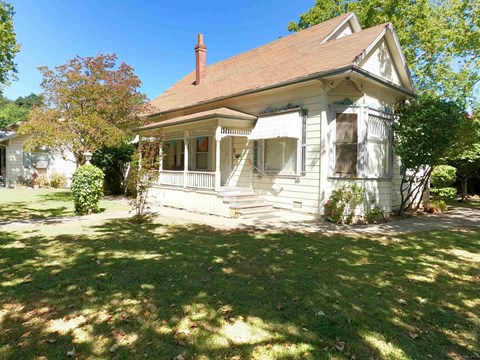 a small white house with a porch and a lawn