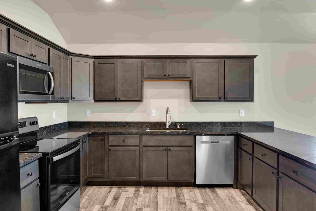 an empty kitchen with black cabinets and a black counter top