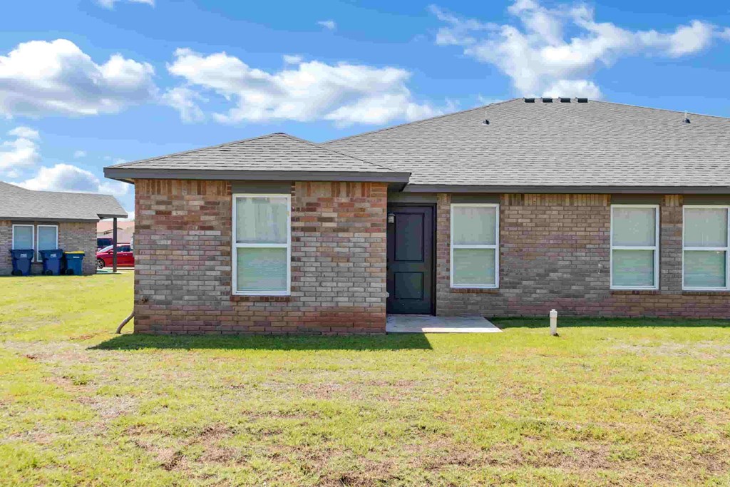 a brick house with a black door and a grassy yard