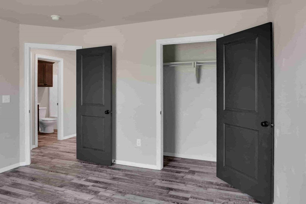 a room with two black doors and a bathroom in the background