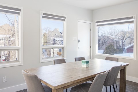 a dining room with a table and chairs and three windows