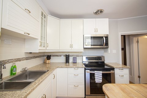 a kitchen with white cabinets and granite counter tops and black appliances