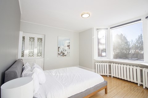 a white bedroom with a bed and a window