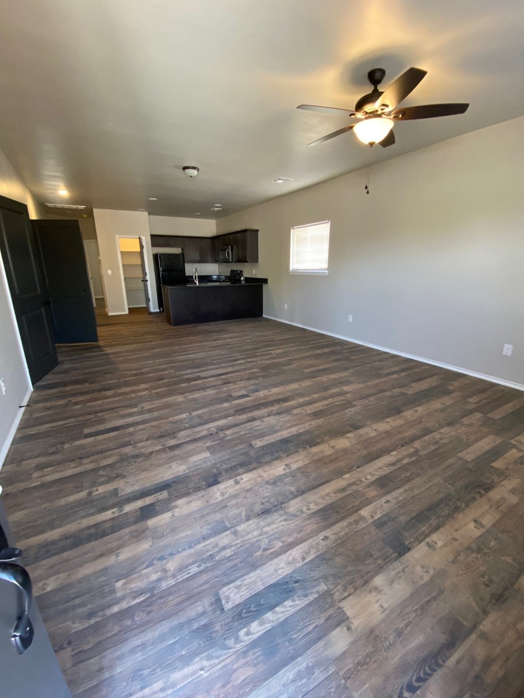 an empty living room with wood floors and a ceiling fan