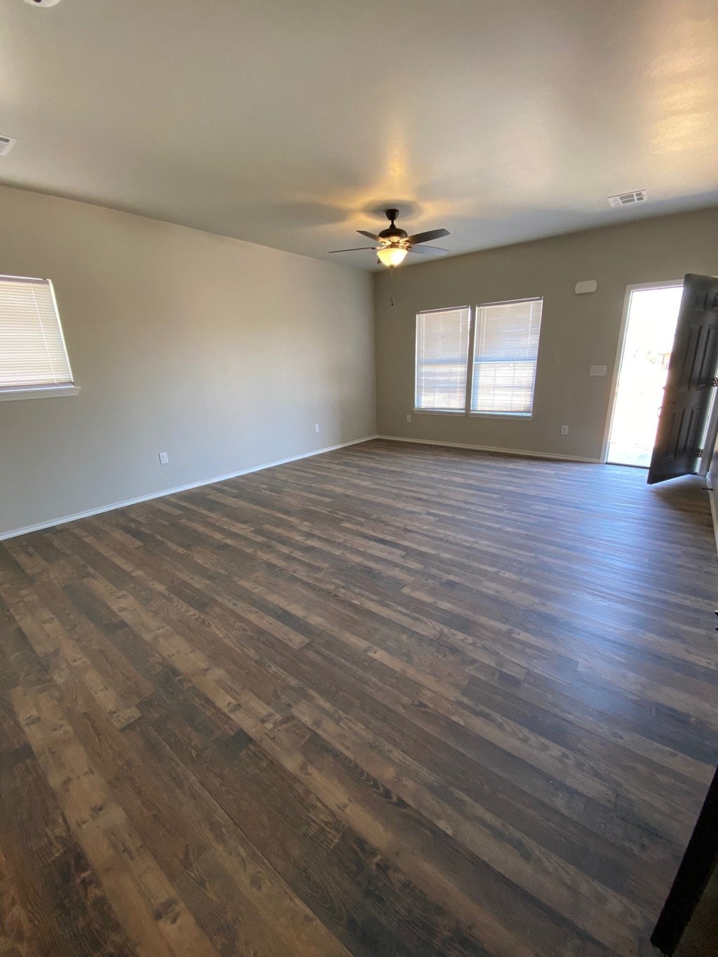 an empty living room with wood floors and a ceiling fan