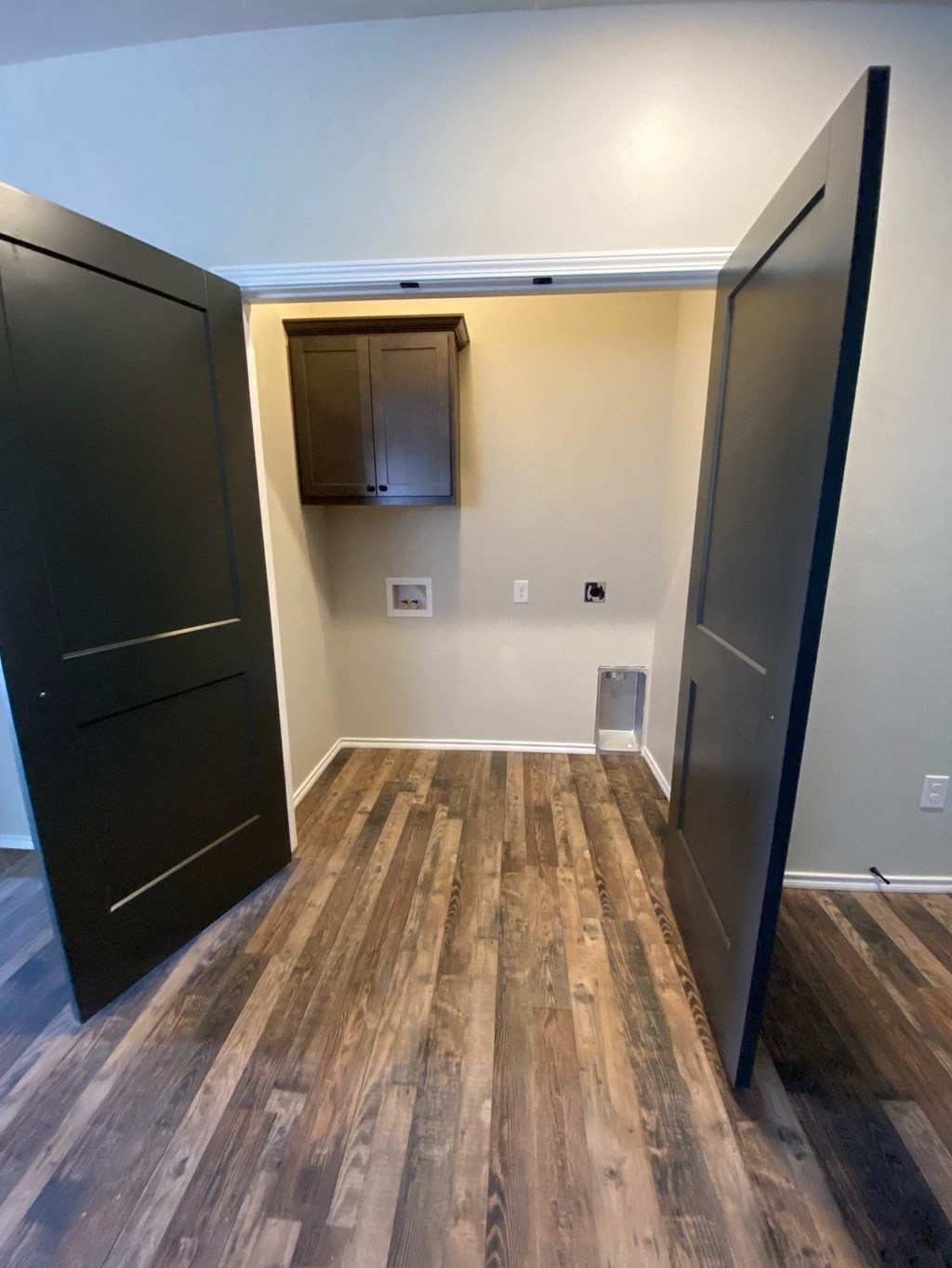 an empty room with two doors and a wall cabinet and a door to a bathroom
