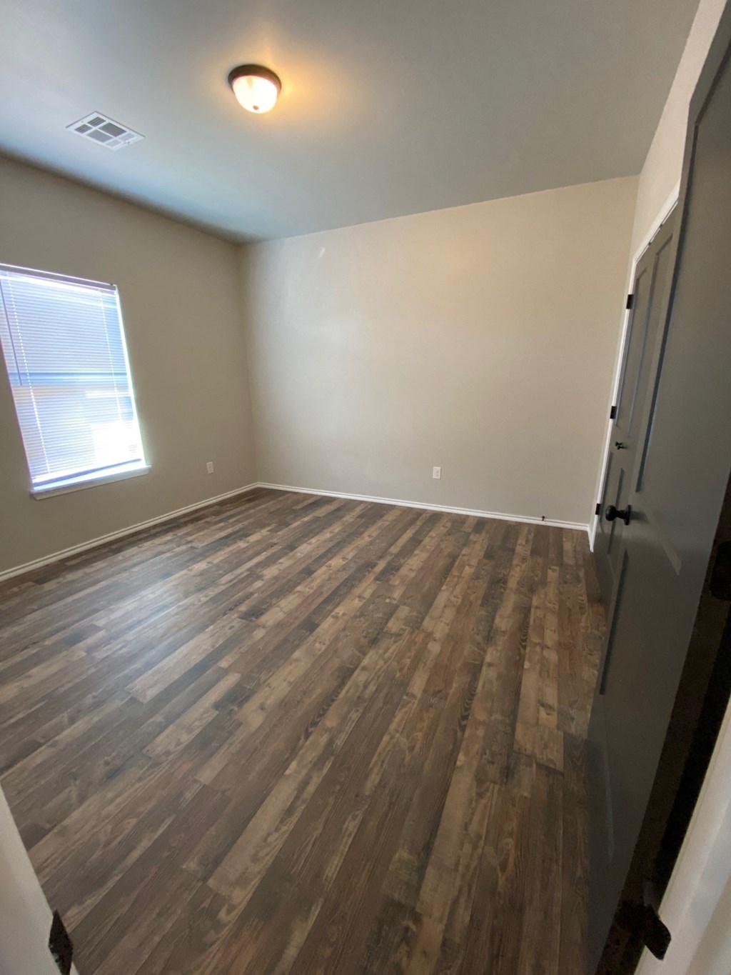an empty room with wood floors and a window
