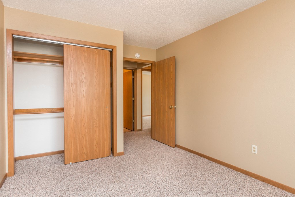 an empty bedroom with two doors and a closet