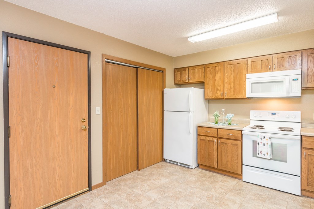 a kitchen with white appliances and wooden cabinets and a refrigerator