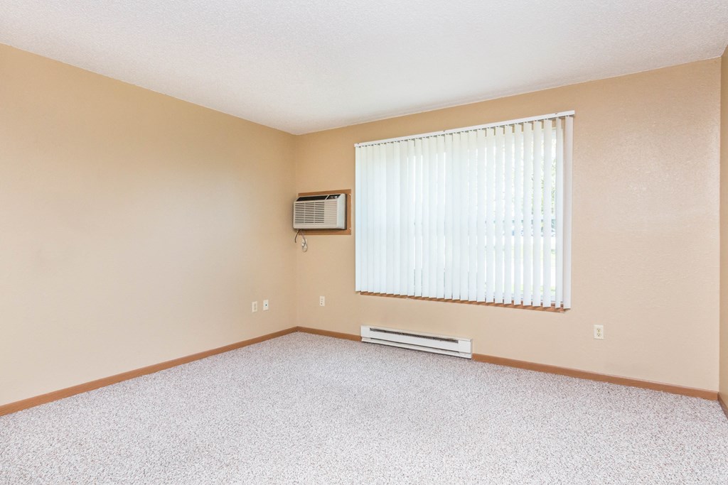 an empty living room with a window and a air conditioner