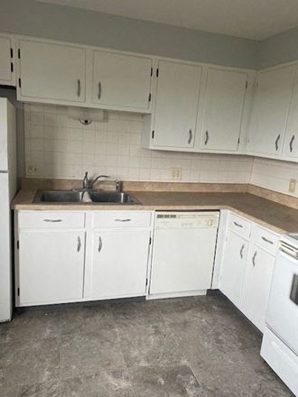an empty kitchen with white cabinets and a sink