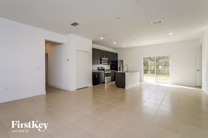 an empty living room and kitchen with white walls and tiled floors